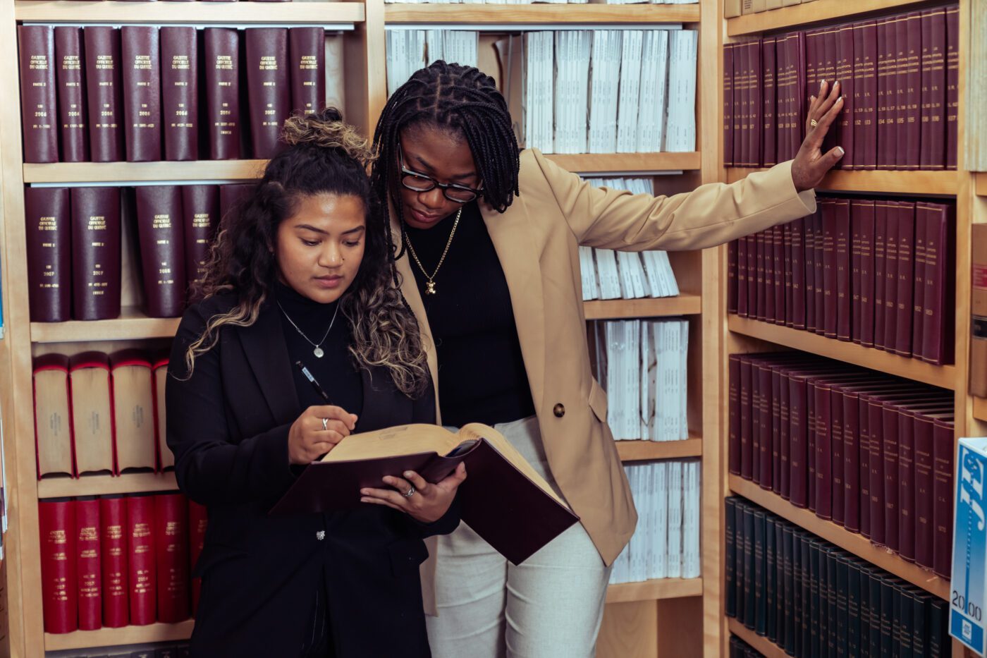 Deux femmes dans une bibliothèque regardant un cahier de notes