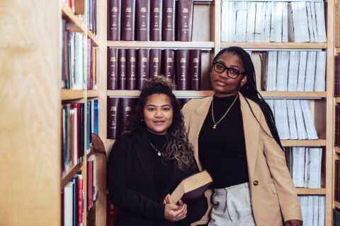 Two-women-in-a-library-with-law-books-looking-at-the-camera